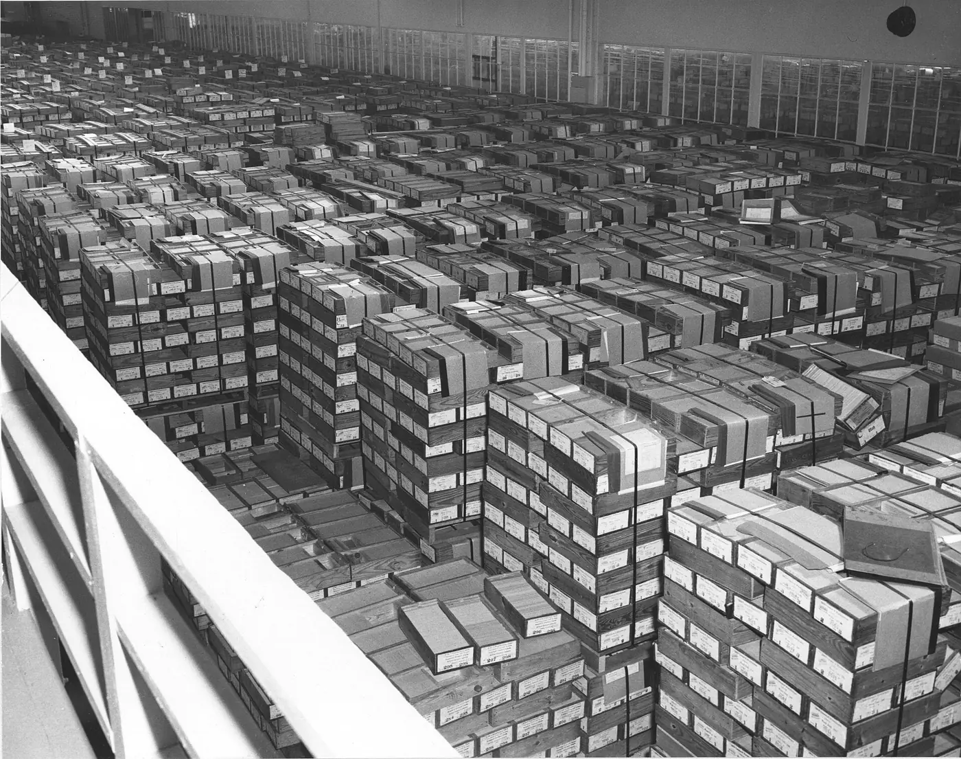 Photo de 1959 vue d'en haut : un entrepôt immense couvert de caisses en bois cerclées, remplies de cartes perforées IBM, empilées à perte de vue.
